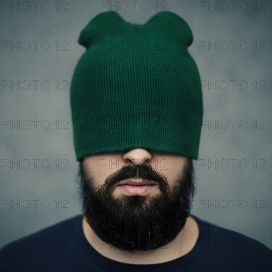 Caucasian man wearing beanie hat over eyes