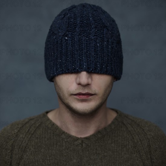 Caucasian man wearing beanie hat over eyes