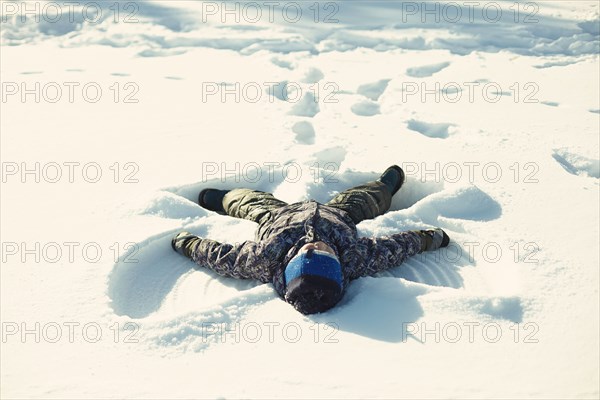 Caucasian boy making snow angel