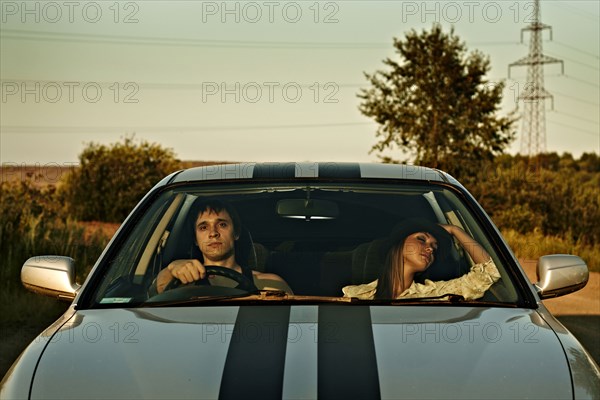 Caucasian couple driving sports car in rural landscape