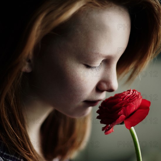 Caucasian teenage girl smelling flower