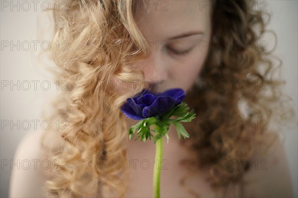 Caucasian teenage girl smelling flower