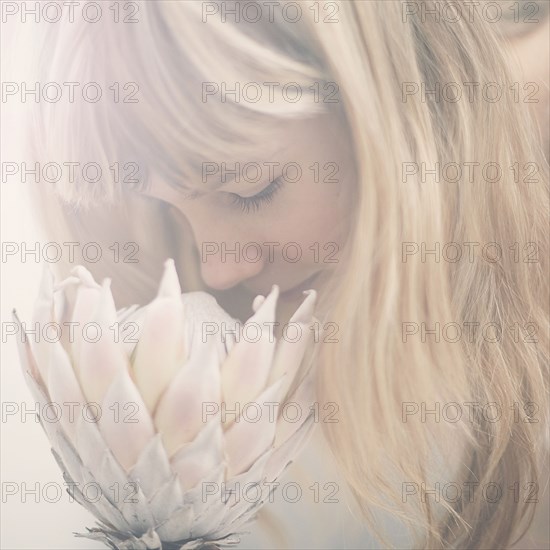 Caucasian teenage girl smelling flower