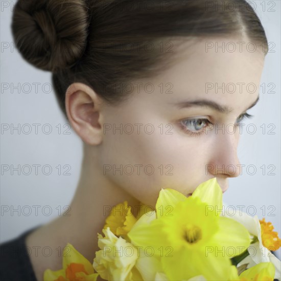 Pensive Caucasian girl holding yellow flowers