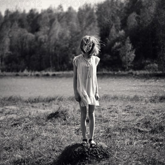 Caucasian girl standing on dirt pile with hair blowing in wind