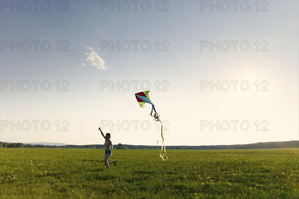 Caucasian girl running in field flying kite