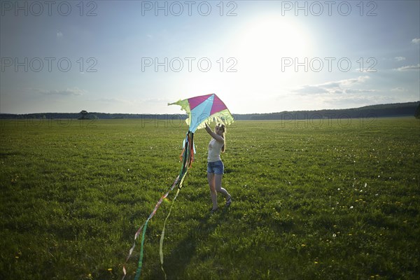 Caucasian girl standing in field holding kite
