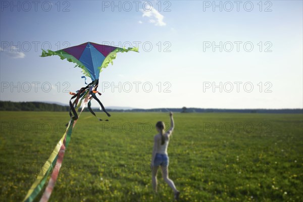 Caucasian girl running in field flying kite