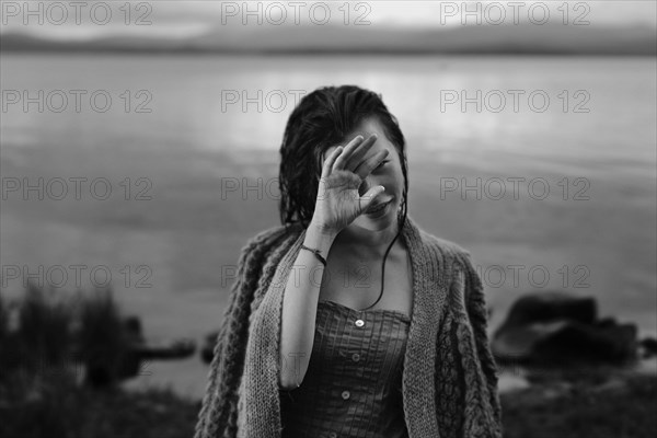 Caucasian girl with wet hair at lake covering face