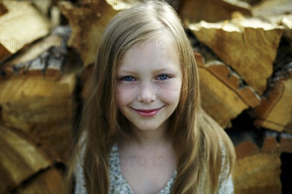 Caucasian girl smiling near woodpile