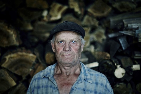 Serious Caucasian man near woodpile