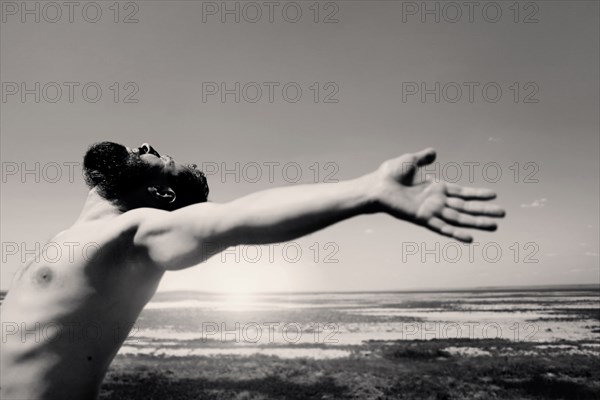 Caucasian man with beard with arms outstretched at beach