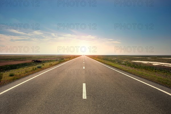 Sunset over distant empty highway