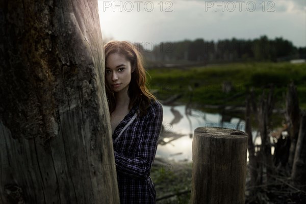 Pensive Caucasian girl leaning on wooden pillar