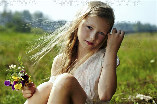 Caucasian girl holding flowers in windy field