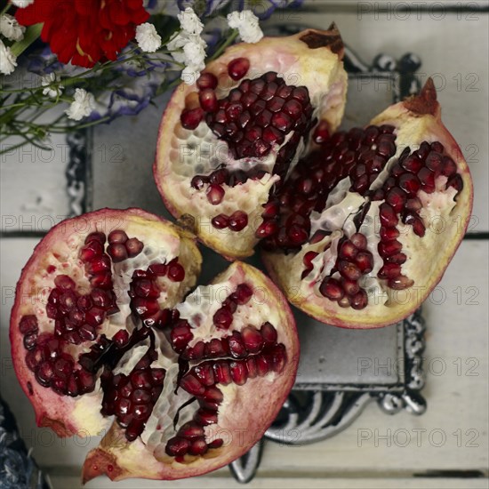 Red seeds in sliced pomegranate near flowers