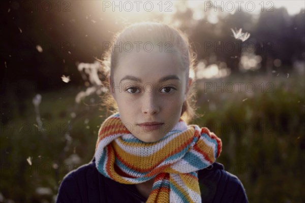 Fuzz floating near face of serious Caucasian girl in forest