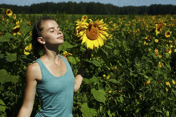 Caucasian girl smelling sunflowers in field