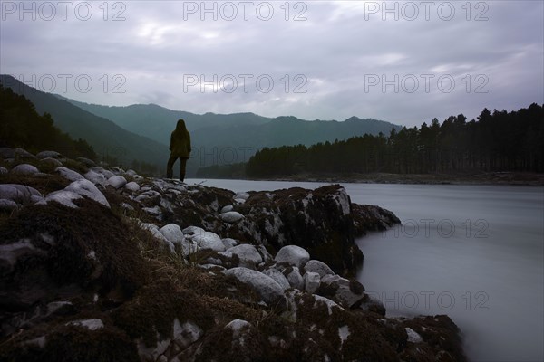 Caucasian girl standing on rocks over foggy river
