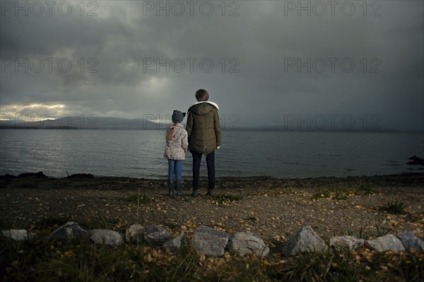 Caucasian sisters holding hands at lake