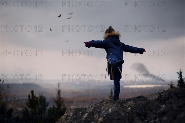 Caucasian girl balancing on rocks imitating flying birds