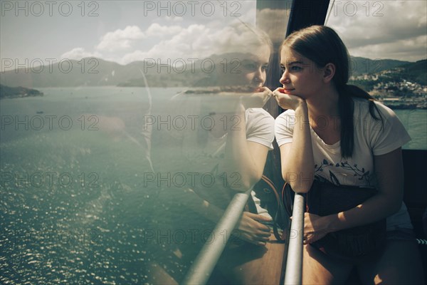 Caucasian woman looking out window on boat