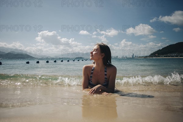 Caucasian woman wearing bikini laying in waves on beach