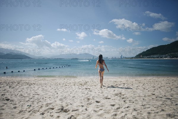 Caucasian woman wearing bikini running on beach