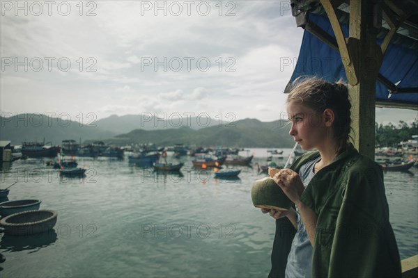 Caucasian woman drinking milk from coconut with straw