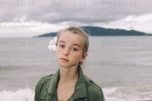 Caucasian woman with flower in hair near ocean