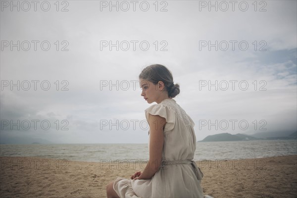 Caucasian women wearing dress sitting on beach