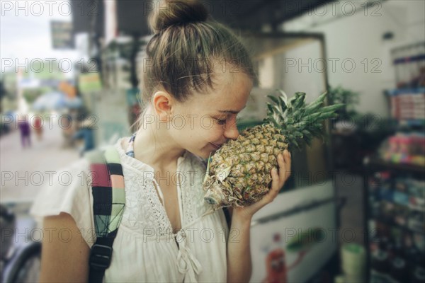 Caucasian woman smelling pineapple at market