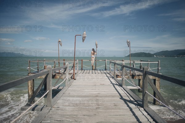 Caucasian woman wearing bikini standing on railing on dock