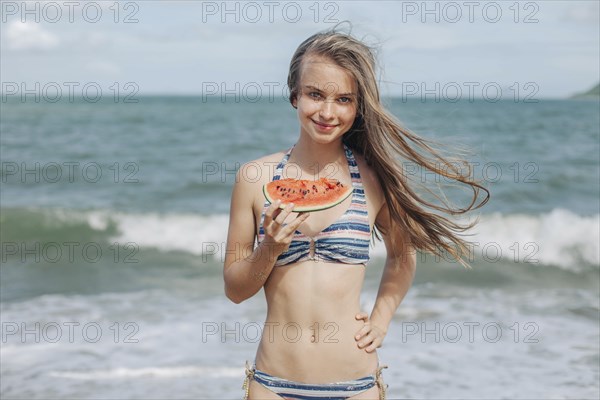 Caucasian woman eating watermelon on beach