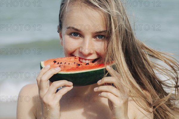 Caucasian woman eating watermelon on beach