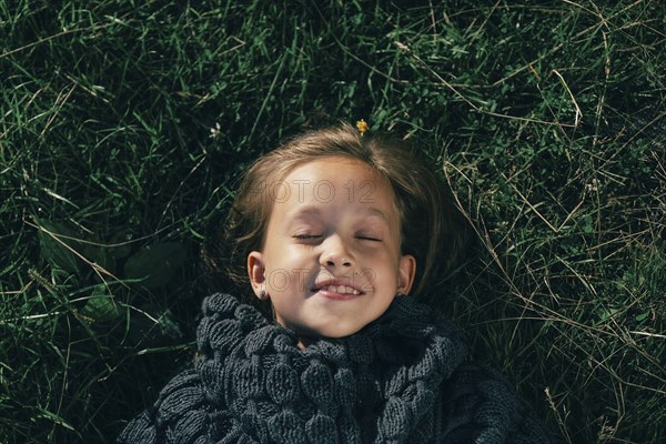 Caucasian girl wearing sweater laying in grass