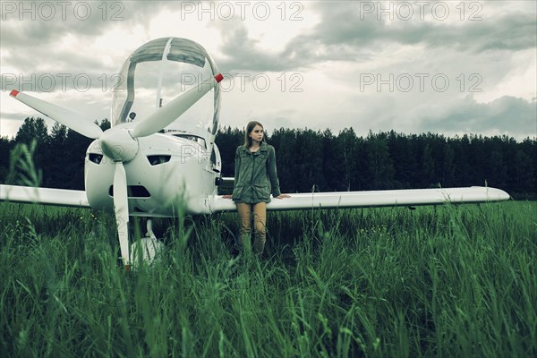 Caucasian woman leaning on airplane wing