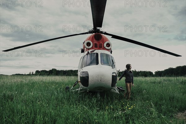 Caucasian woman standing near helicopter in field