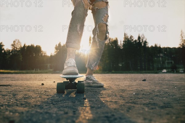 Legs of Caucasian teenage girl standing on skateboard