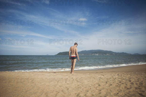 Pensive Caucasian man standing on beach