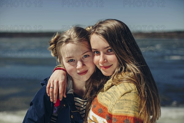 Caucasian sisters hugging on beach