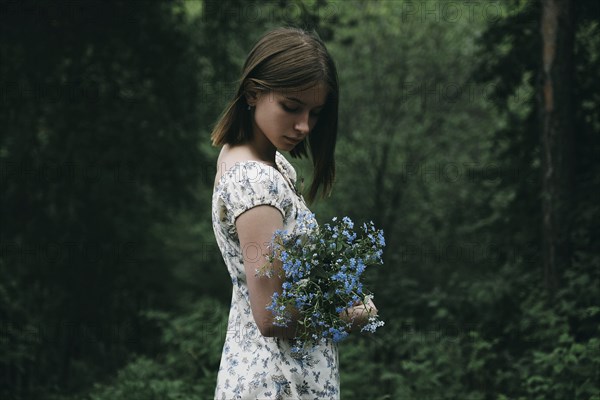 Caucasian woman holding flowers in forest