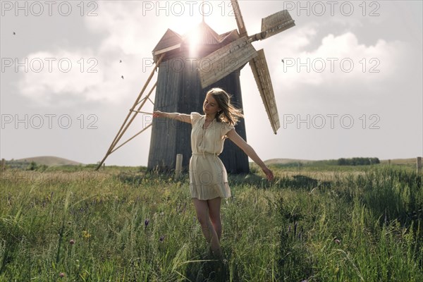 Caucasian woman balancing in grass near windmill