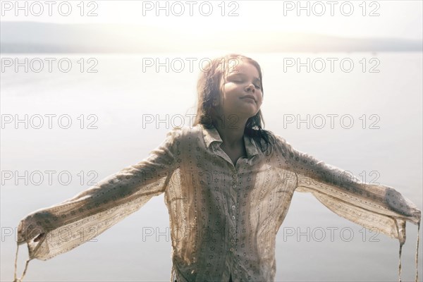 Caucasian girl wearing wet shirt near sunny lake