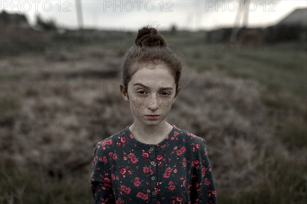 Caucasian girl with freckles raising eyebrow in field