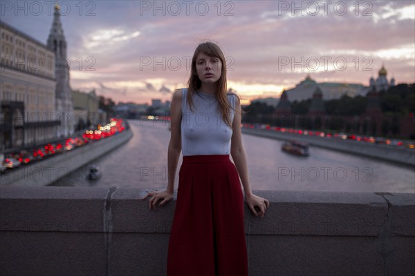 Caucasian woman leaning on bridge over urban canal