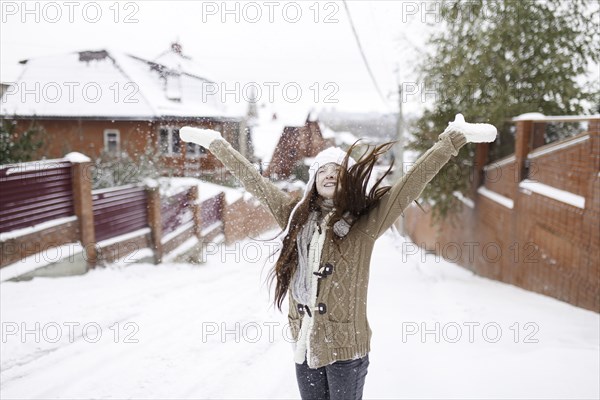 Caucasian girl throwing snow outdoors