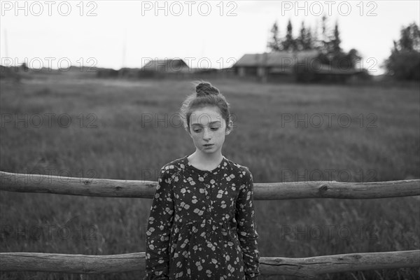 Caucasian girl standing near wooden fence