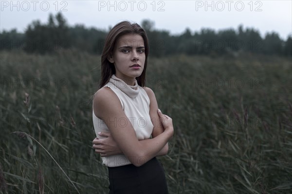 Caucasian teenage girl standing in field worrying