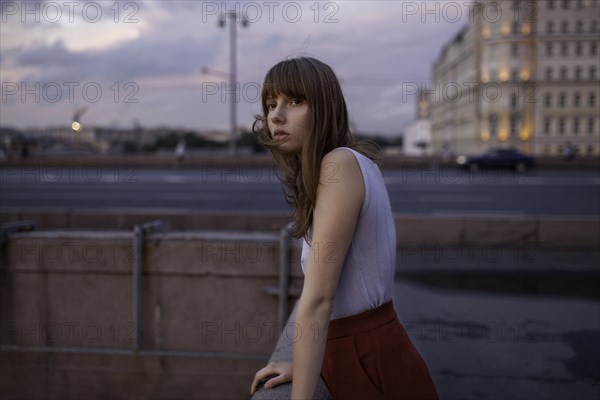 Serious Caucasian woman leaning on wall in city